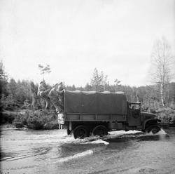 Soldater henger bakpå en militær lastebil.