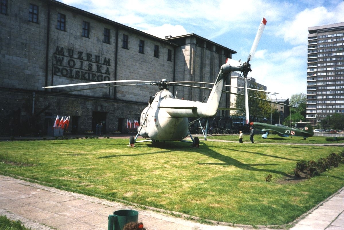 Landskap. Et militært Helikopter er blant objektene som står oppstilt på et utstillingsområde for flyinteresserte besøkende.