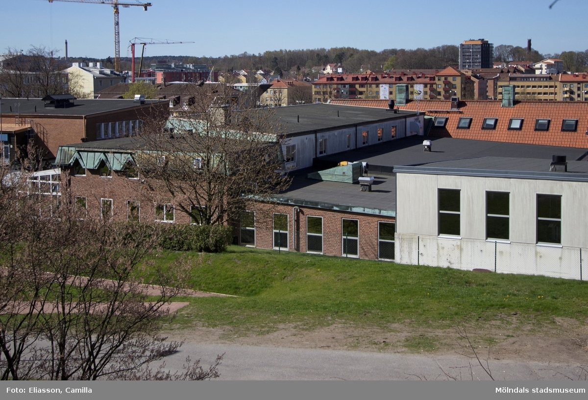Den bild är tagen strax bakom nuvarande Mölndals brandstation. Här ser man brandkårens område och all den bebyggelse som vuxit upp i närheten. En lyftkran står mitt i nybygget av SCAs stora vita kontorsbyggnad. Till höger, på andra sidan motorvägen, ligger Mölndals centrum samt det mörkgråa höghuset som ligger på Storgatan 32A.