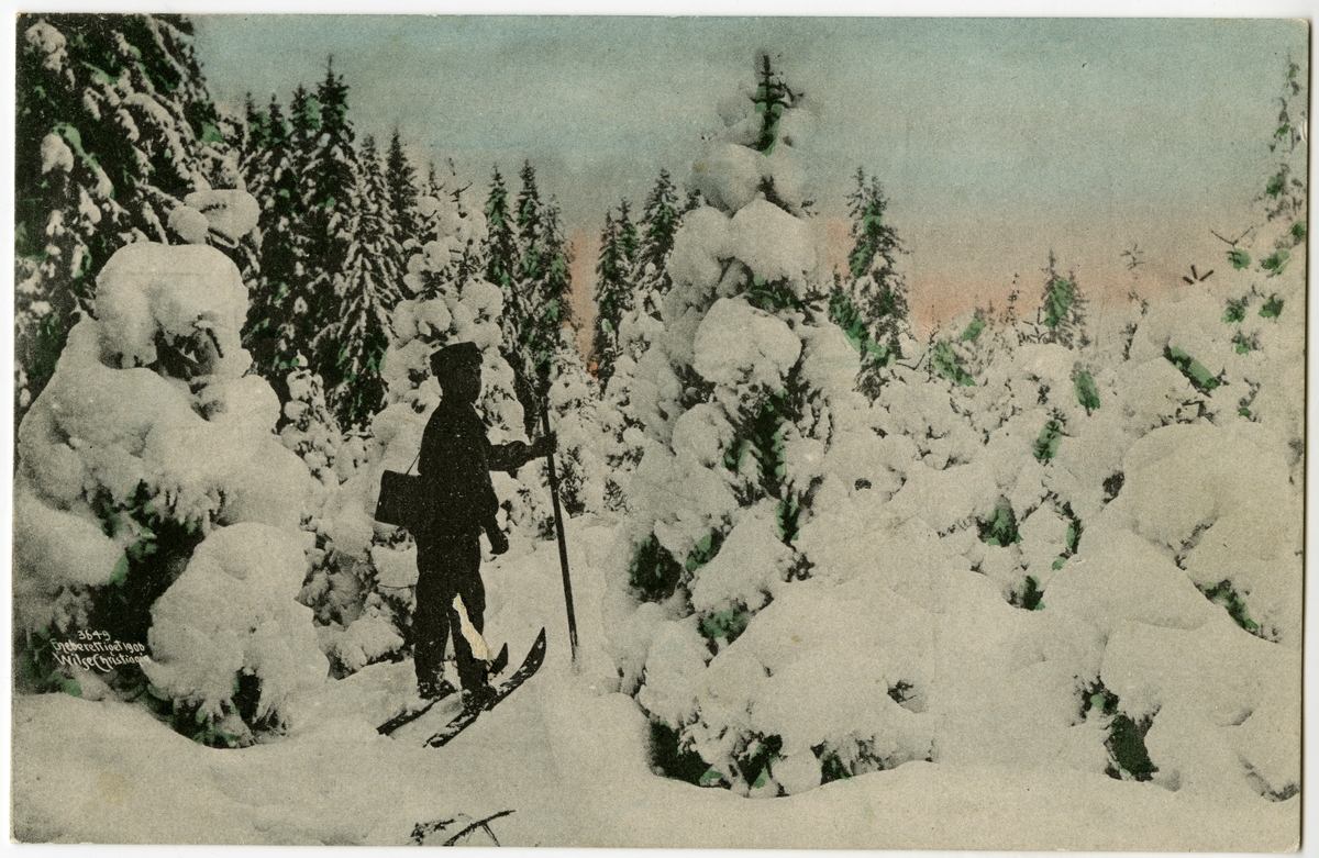 Kolorert postkort. Skiløper i skogen med snøtunge trær.