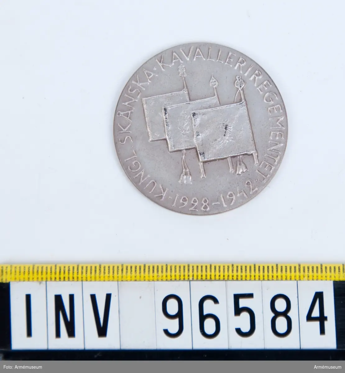 Medalj i silver för Skånska kavalleriregementet.
Stans 14513, härdad 1942-10-21.
Medalj, storlek 40 mm diameter, åtsida med tre standar inom omskrift KUNGL. SKÅNSKA KAVALLERIREGEMENTET 1928 1942, enligt modell av skulptören Karl Hultström.