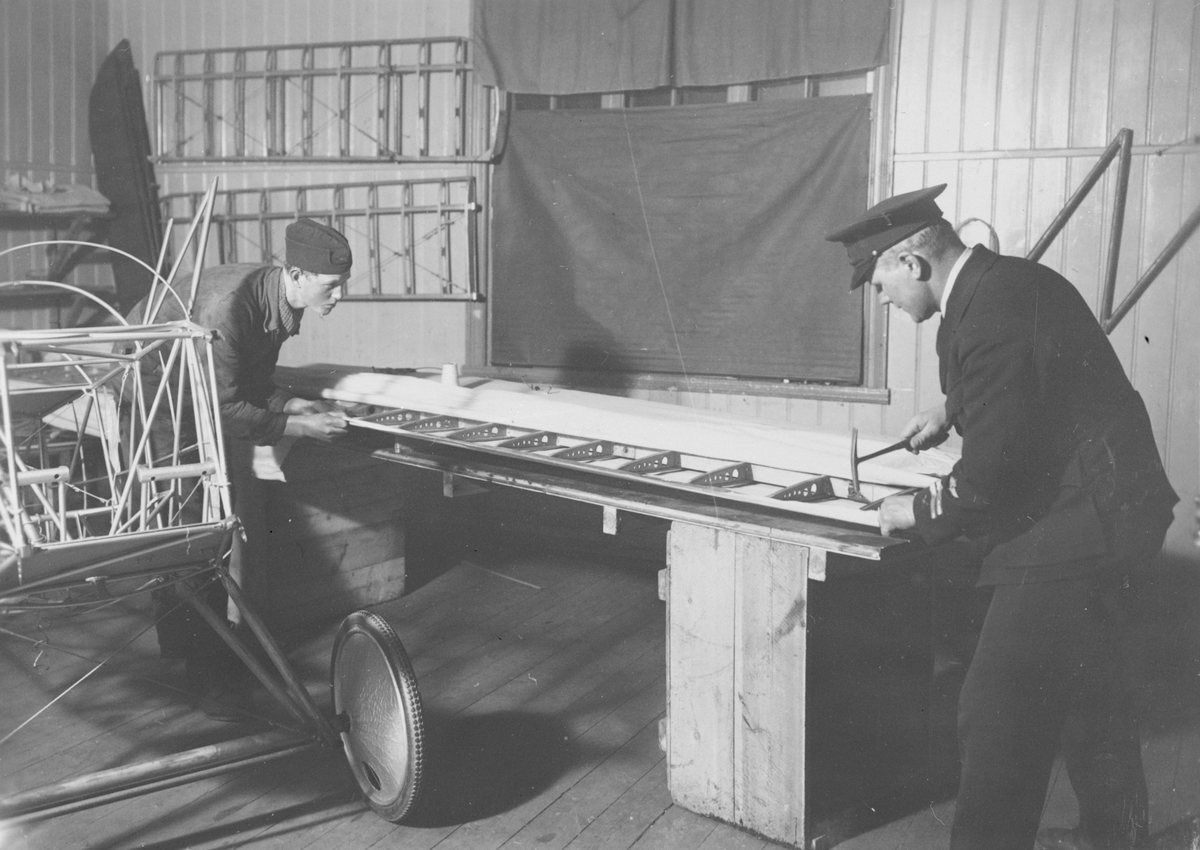 Flygplansbygge. Tyghantverkare George Holmberg och okänd miltiär i arbete med att klä en flygplansvinge med duk på flygplanet Holmberg Racer.