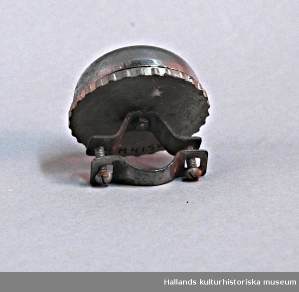 Pappask i rött och svart (1). Ringklocka (2) i metall, konstruerad för att monteras på cykelstyre med två skruvar.