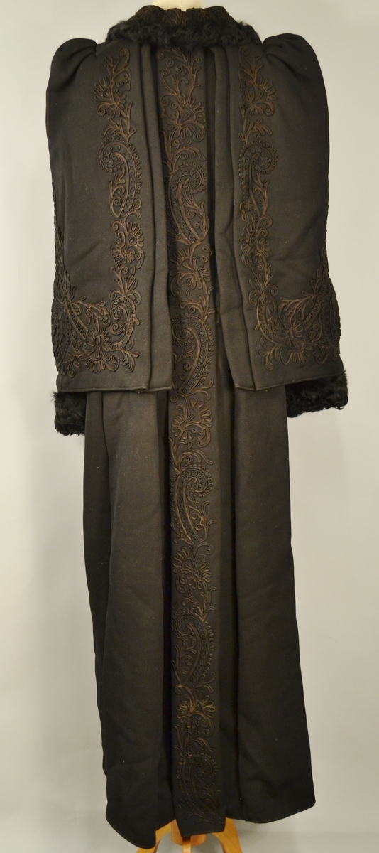 Kåpen er helforet med silkefor. Den består av kåpe med en fastmontert cape. Den er dekorert med lissebroderier i silke på krage og cape.