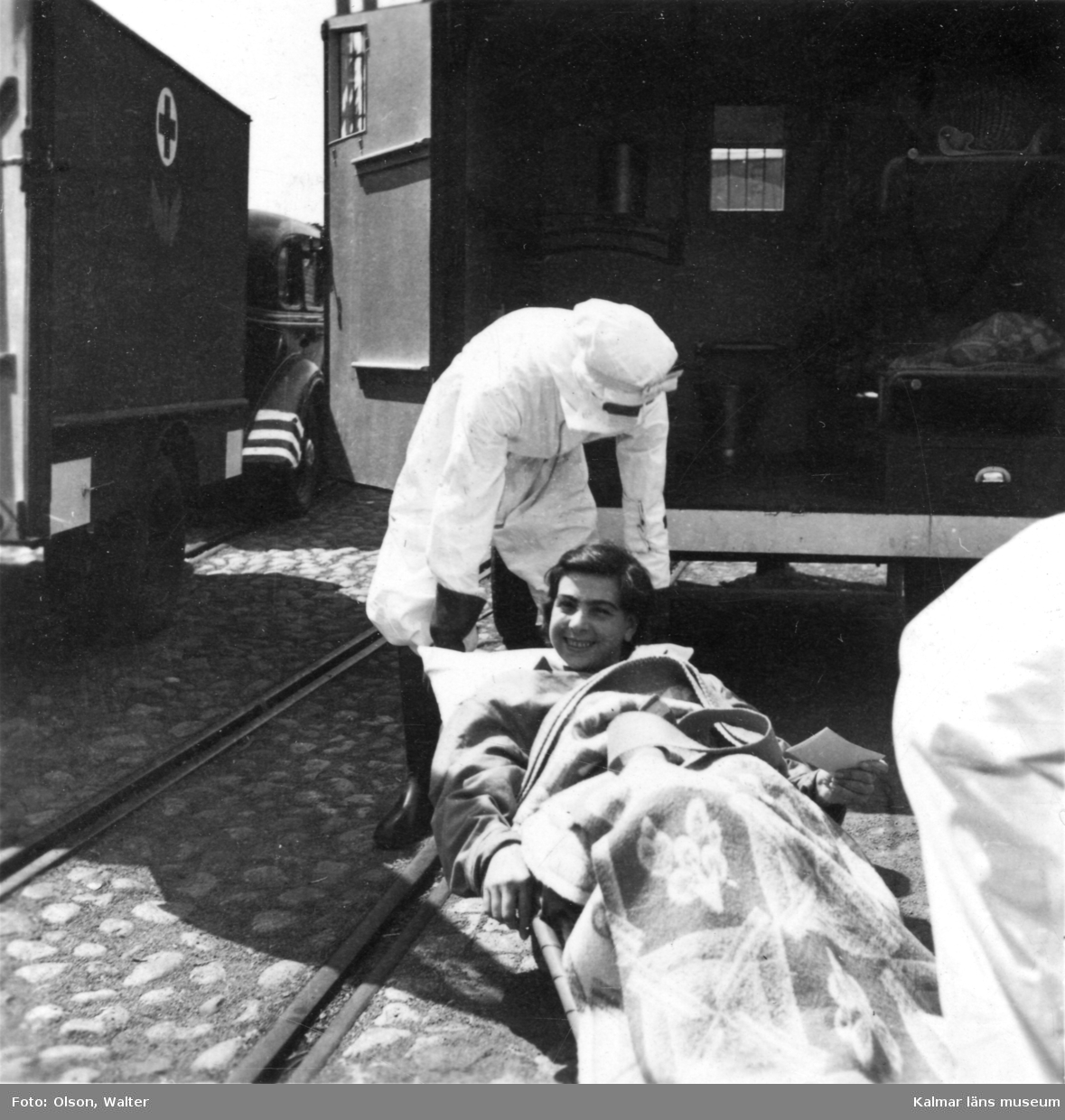 En ung kvinna som varit fånge i Bergen-Belsen anländer till Kalmar med skeppet Prins Carl och lyfts ombord på en lastbil. Observera mottagarnas andningsskydd! Många patienter hade tyfus och TBC.