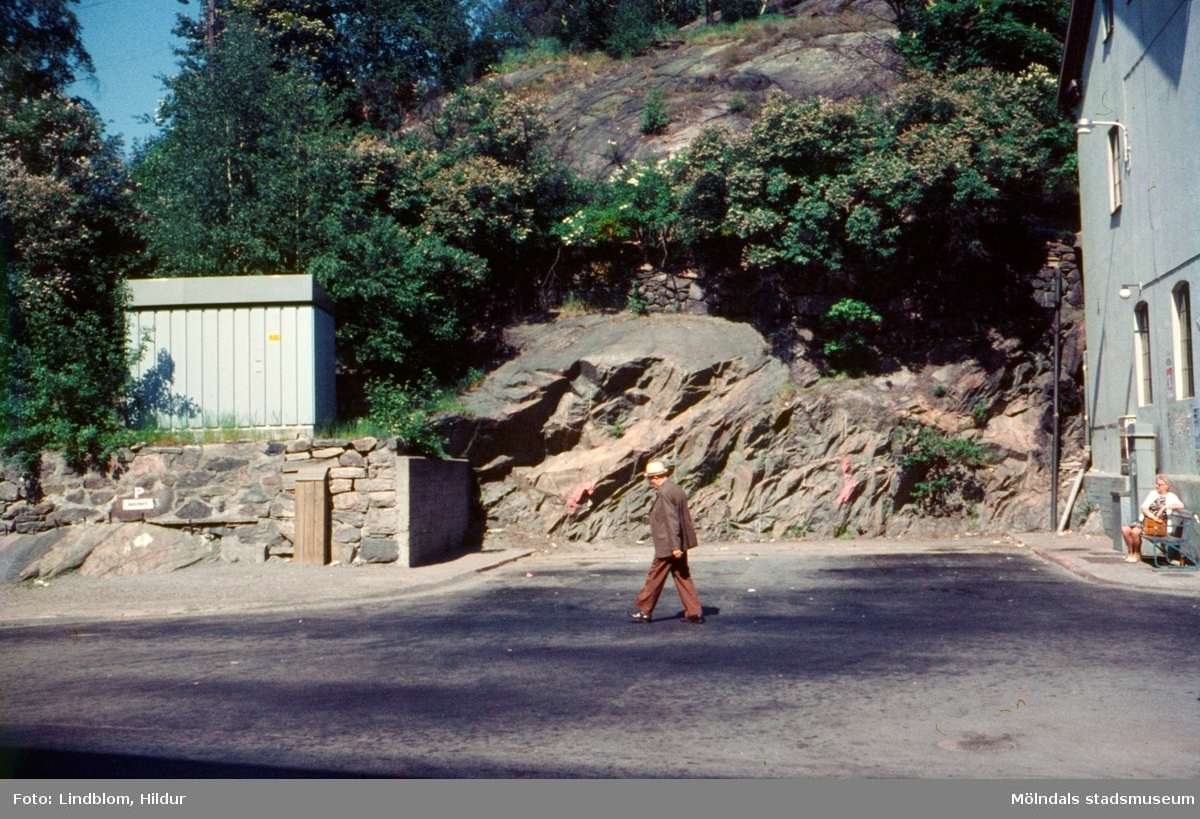 En man går förbi busshållplats vid Gamla Torget i Mölndal, 1970-tal. Till höger ses gaveln på huset Kvarnbygatan 41, tidigare brandstation och garage för polisbilar, numera Mölndals målarskola.

För mer information om bilden se under tilläggsinformation.