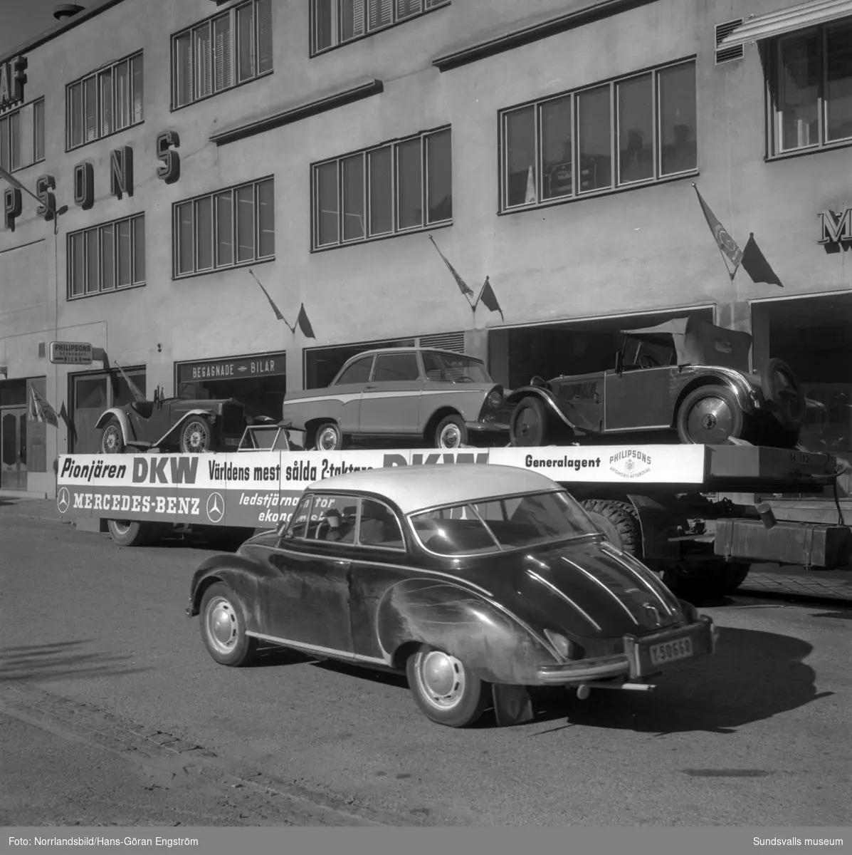 Tre veteranbilar av märket DKW står på en trailer utanför Philipssons vid Norra Järnvägsgatan.