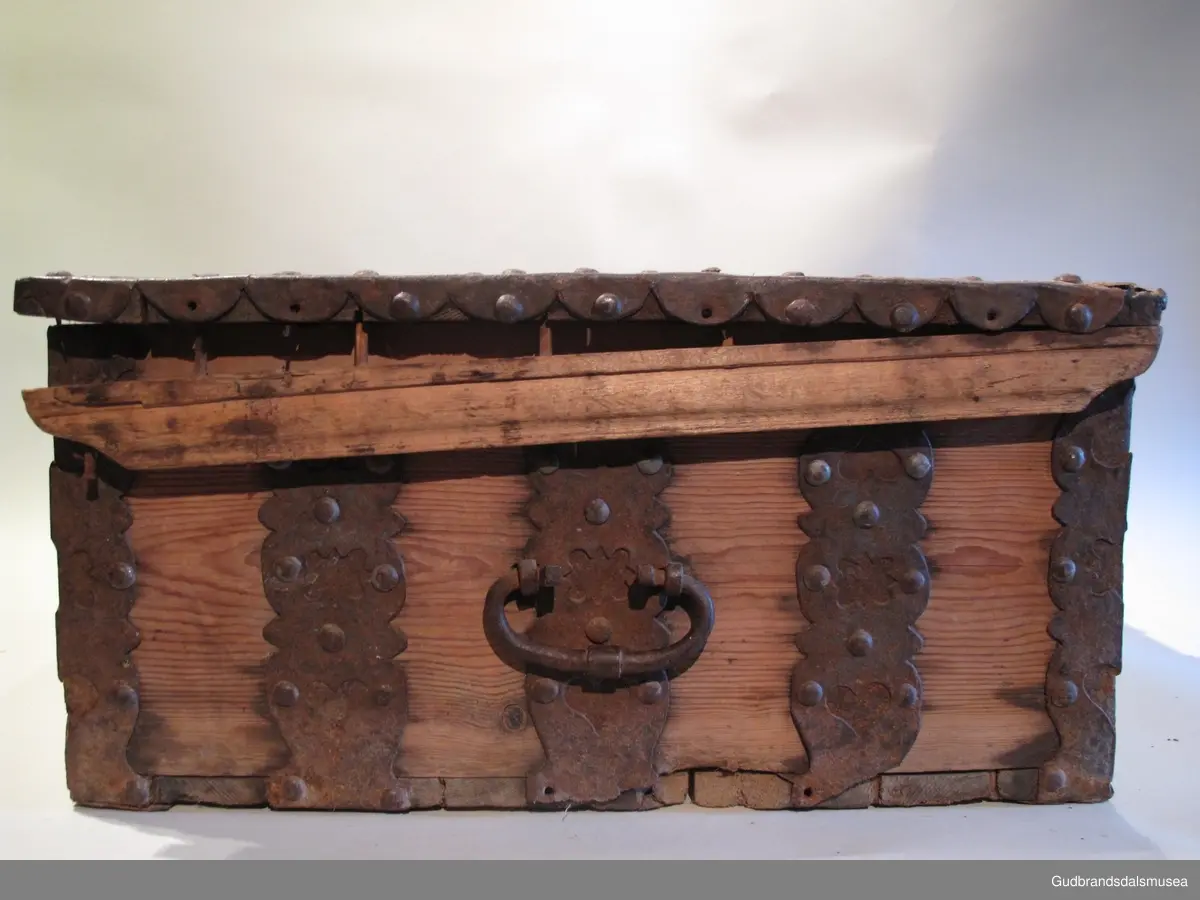 "Ferdaskrin. Umalt. Over heile skrinet går det beslag med innhogga stjerner og hjerter. Fra Østre Gausdal. Merknad 2, også kalla Føringsskrin" (Jf. Katalog for Lom Bygdesamling, 1925).
Skrinet har 1 rom. LOKK: satt sammen av 3 bord, holdt sammen av sidelister på innsiden og jernbeslag langs sidekanter på oversiden. Hengslet med 2 hengselbeslag på innsiden og  2 på utsiden av bakstykke.  1 stk. låsbeslag på innsiden av lokk.
SKRINSIDER: gjæra sammen, holdt sammen av hjørnekantbeslag utvendig; profilerte toppkanter.
BUNN: satt sammen av 2 bord, festet til skrinrammen med trenagler. Er i tillegg opprinnelig holdt på plass av 10 beslag festet til skrinbunn og sidestykker. Jernhandtak på hver side.
BESLAG: 5 jernbeslag i lengderetning på lokk. Tilsvarende 3 beslag og 2 hjørnebeslag på front og sider. Alle beslag er festet med jernnagler.
DEKOR. Ingen skurd- eller malingdekor. Skrinet har i stedet jernbeslag med utskårne hjerte- og stjerneformer som dekor. Muligvis fra 1600-tallet der treskurden ikke var fremherskende. Liknende dekor ses på LBY0319.
BRUK. Før kofferten kom i bruk hadde man reiseskrinet, som ble brukt til oppbevaring av bl.a. klær, verdisaker og mat på reiser. Skrinet hadde ofte et eller to mindre, smale rom langs den ene skrinsiden og ett større rom. De fleste reiseskrin var i tillegg forsterket med jernbeslag langs alle kanter og med en solid nøkkelhullås til sikring mot støt, slag og tyveri.