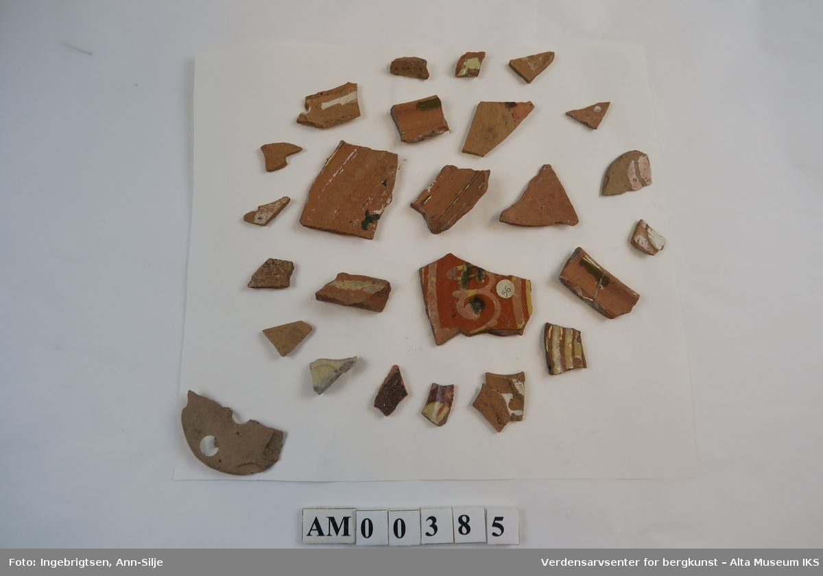 Et ark med mange keramikkfragmenter i ulike størrelser. Noen av fragmentene har rester etter glasur. 

Keramikkfragmentene varierer i størrelser fra 1,5 cm til 5,5 cm i lengde.