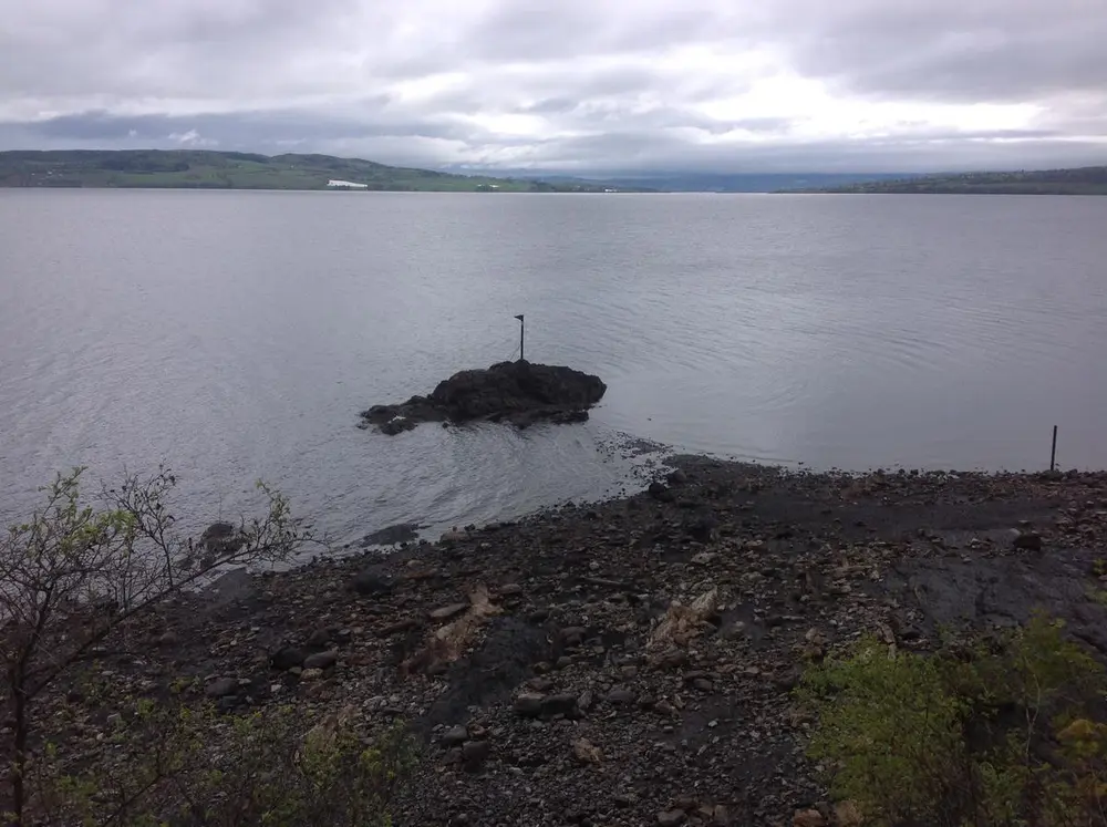 Mørkt bilde av Sjøormskjæret som stikker opp av Mjøsa.