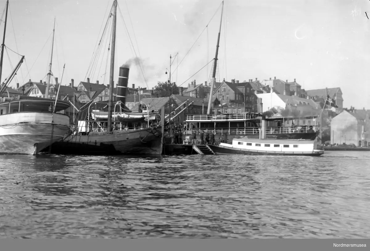 Et bilde tatt ute fra havnebassenget ved Piren på Kirkelandet i Kristiansund. Her ser vi tre større passasjerbåter liggende, samt  en av byens sundbåter som gikk i traffikk mellom byens øyer. Fra Nordmøre Museums fotosamlinger.