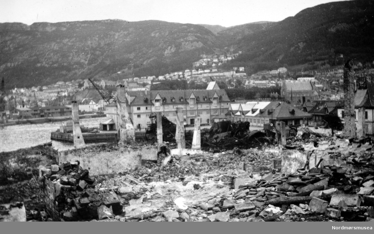 
Foto fra et tettsted i ruiner. - Dette er fra bydelen Nordnes i Bergen, som ble bombet av britiske fly i april 1940. Den intakte bygningen i bakgrunnen står på Tollbodkaien. (Informant: Arne Stein Pedersen.)





