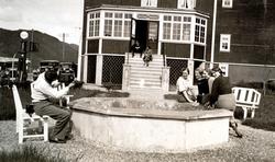 Foto av fire kvinner og en mann i forgrunnen sittende rundt 