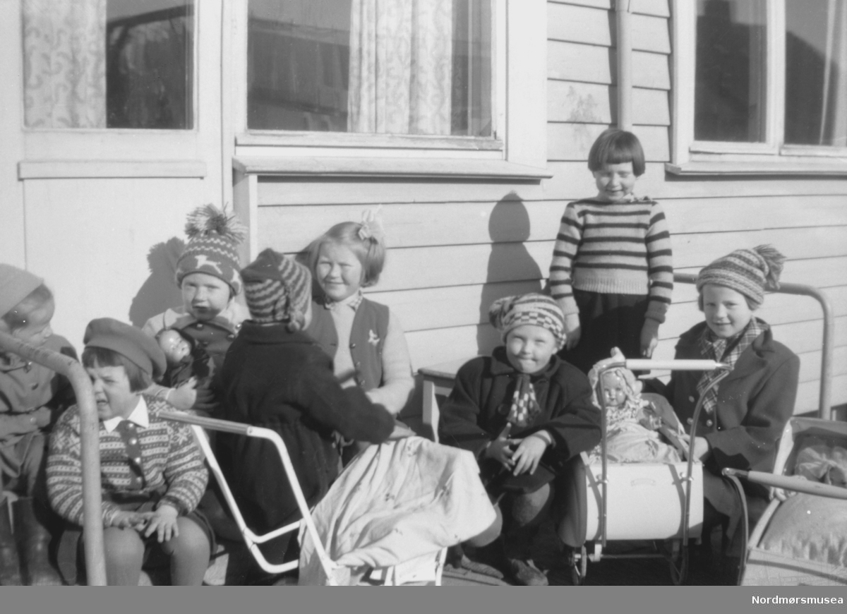 Her ser vi en gruppe barn ute på terrassen til en bolighus. Trolig enten familie, slekt eller bekjente av fotografen, som sannsynligvis er John Myren. Datering er ukjent, men trolig mellom 1930 til 1960. Stedet er også ukjent, men kan være fra Sunndal kommune. Fra Nordmøre museums fotosamlinger.

