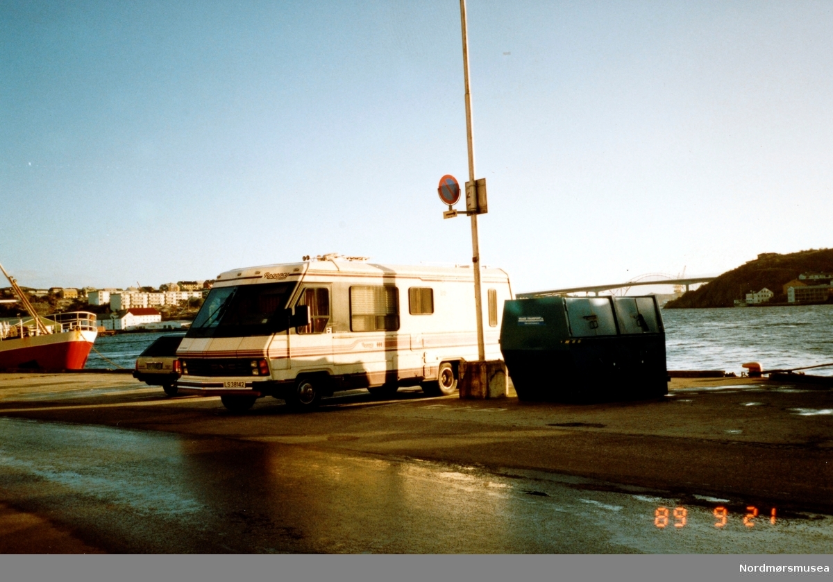 Foto av en campingbil stående på Kaia på Kirkelandet i Kristiansund, med Nordsundbroen i bakgrunnen. Bildet er datert 21. september 1989. Fra Nordmøre museums fotosamlinger. Reg: EFR
