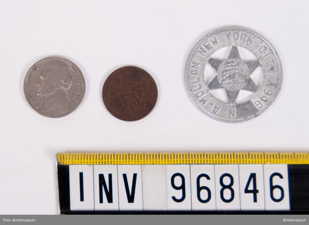 Tre stycken amerikanska mynt av varierande utseende och valör. Ett är värt 1 cent, ett är värt 5 cent och ytterligare ett (det med en stjärna i mitten) har möjligen fungerat antingen som en polett eller ett minnesmynt.