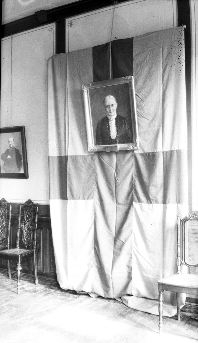 Målat porträtt av Karolina Själander hängandes över en svensk flagga.