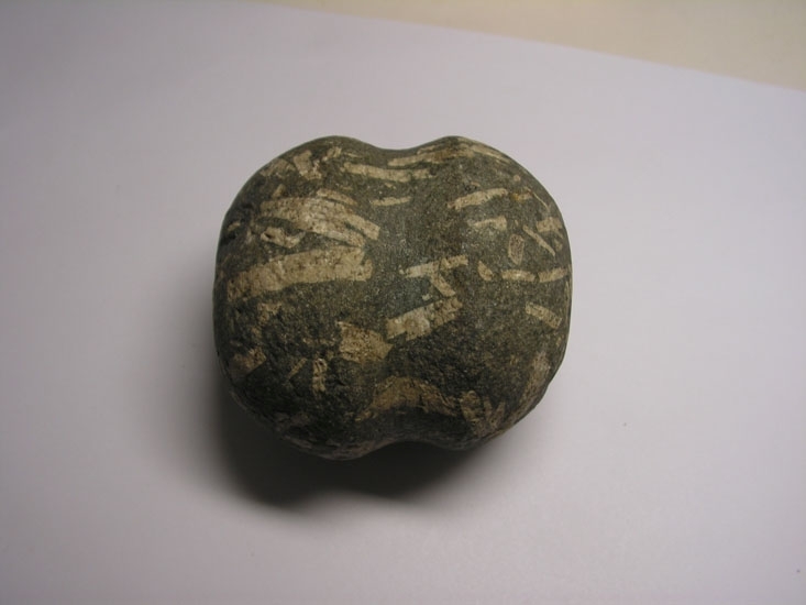 Ev. sänke av grönstenspofyrit. Ovalt formad sten med en cirkelformad ränna/fördjupning som löper runt mitten. Föremålets syfte är inte är helt tydlig. 
Inskriven i huvudboken: 1891