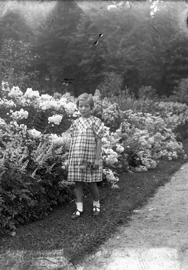 Foto av en liten flicka vid en blomsterrabatt i en park. - Kulturparken ...