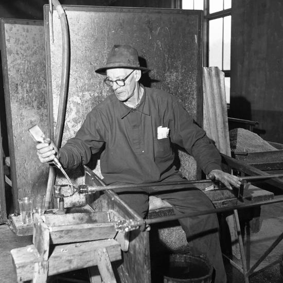 En man som sitter på en glasarbetarstol och arbetar.