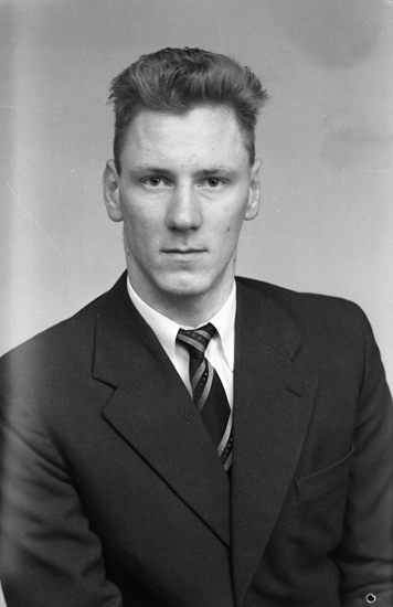 Foto av en man i mörk kostym och slips.
Bröstbild. 
Stig Frisk (senare Magnell), (1937-   ), Norra Vare Norregård, komministerboställe, Blädinge.
Jfr MINI1526 och MINI1579.