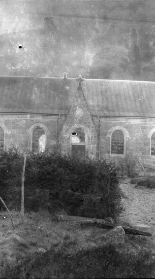 Foto på en kyrka från sidan, med en buske längst fram.
Hamneda kyrka.