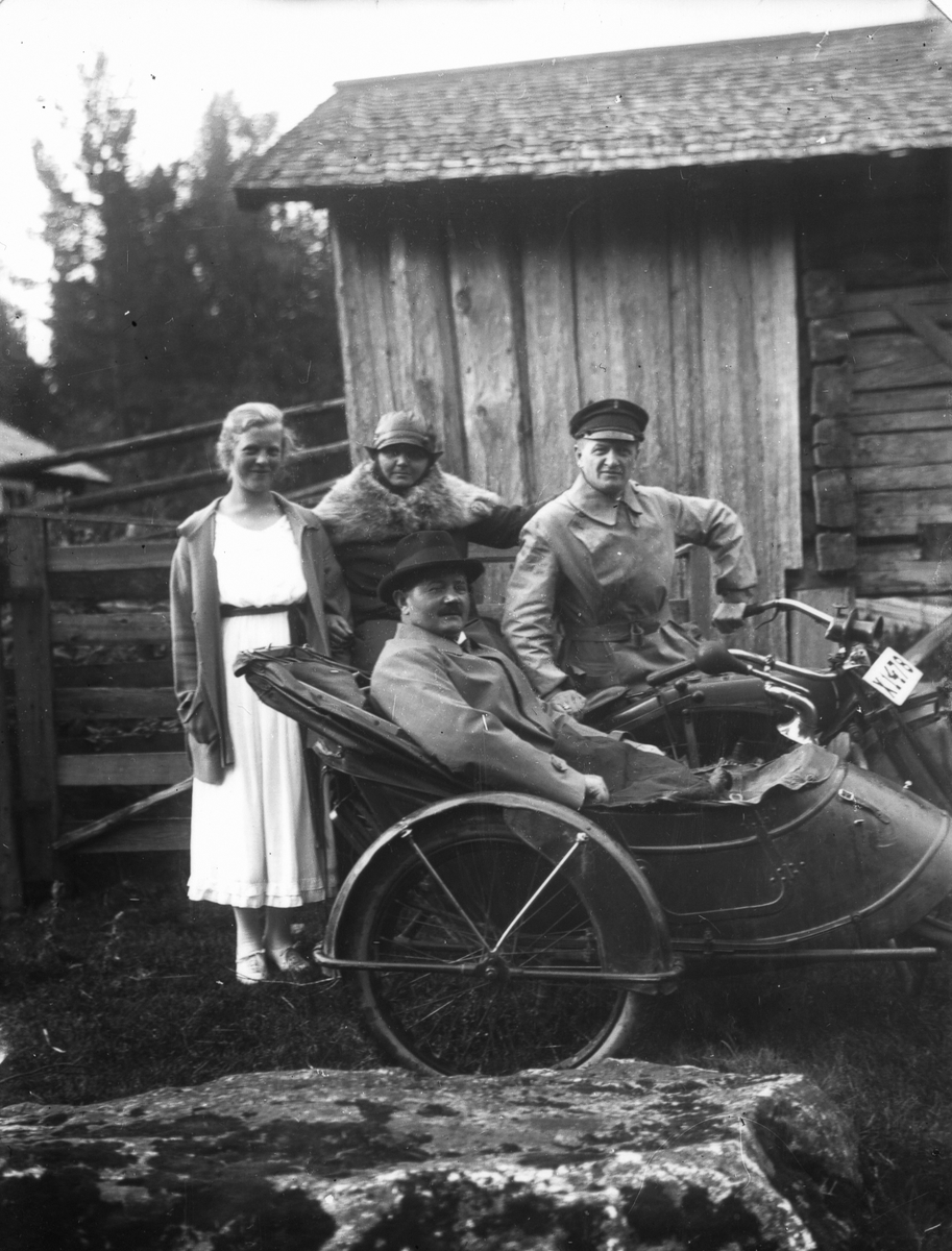 Grupporträtt, två män på motorcykel med sidovagn, två kvinnor.
Mototcykeln är en Iver Johnson, producerad i USA.
