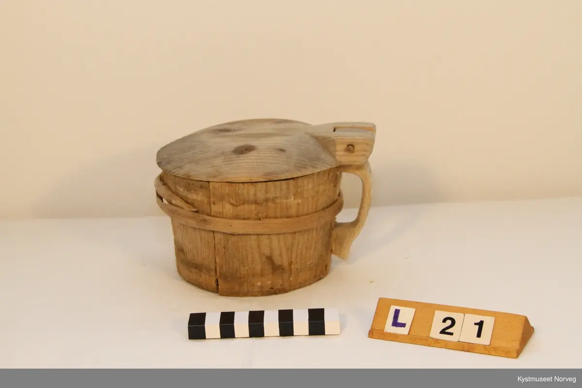 Smørkoppen er brukt til oppbevaring av smør. Treband; to nederst og et øverst. På lokke hank av jerntråd.