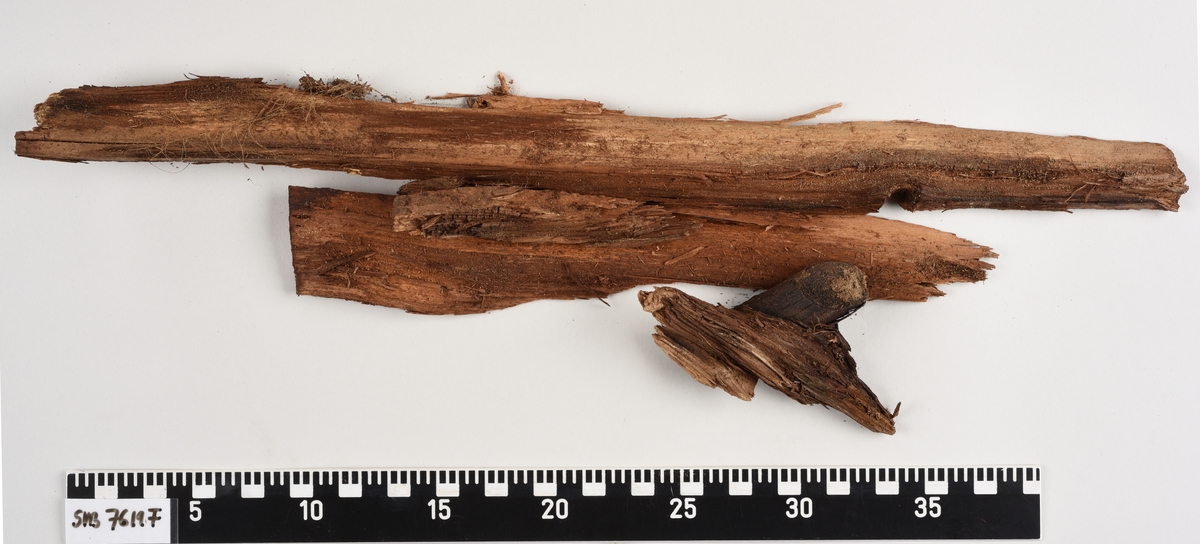 Deler av en rektangulær gravkiste. Det er kistebunnen, kistelokk, kistesidevegger og deler av hodeendegavlen.
Kistelokket er laget av et flatt og rektangulært bord som er laget av ett stykke tre. Bordet er sterkt fragmentert.
Kistesidene er i litt bedre tilstand. Bordene er avlange, rektangulære og laget av et stykke tre hver. Bordene ble festet med spiker til kistebunnen. Det er en spiker igjen i venstre sideveggen. Begge sidebordene har langsgående sprekker og er delvis brudd i flere deler.
Kistebunnen er laget av et flatt og rektangulært bord som er laget av ett stykke tre. Det er flere langsgående sprekker og flere kvisthull. Fargen er mørk brun med enkelte lysere brune partier i hodeenden.  I begge kortender er det rester etter hodegavlen og fotendegavlen og langs venstre siden er det rester etter kisteveggen. Hodeenden er bredere enn fotenden.
Hodeendegavlen er laget av en tykkere rektangulær trekube. Den har brudd opp i flere deler både på grunnen av nedbrytingen og under utgravningen.