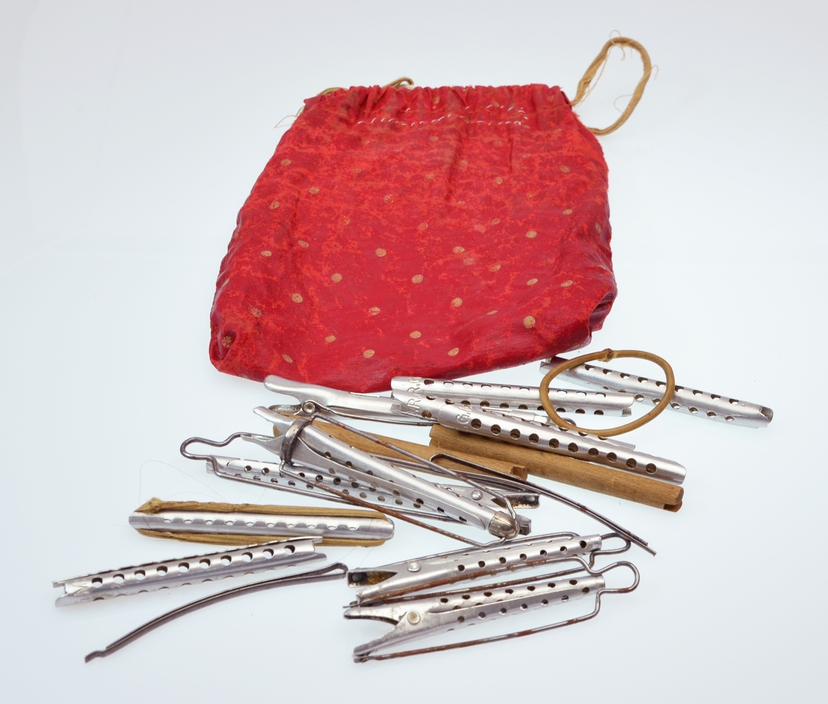 Ein tøypose med krøllpinner, metallspenner og strikk og eit papir med bruksrettleiing til krøllpinnane.