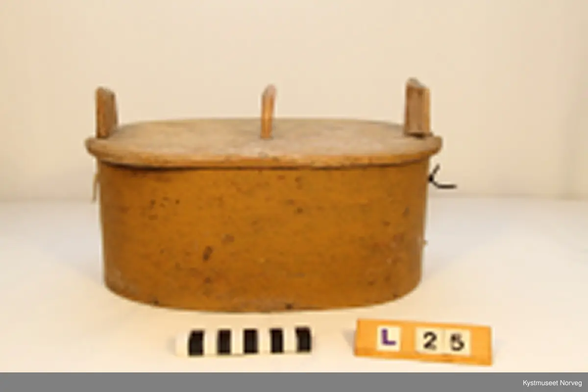 Oval utforming. Laupen har lokk som er innfelt i to trestykker som er festet i siden på laupen, hvor det ene trestykket er dreibart, og utgjør feste for lokket.