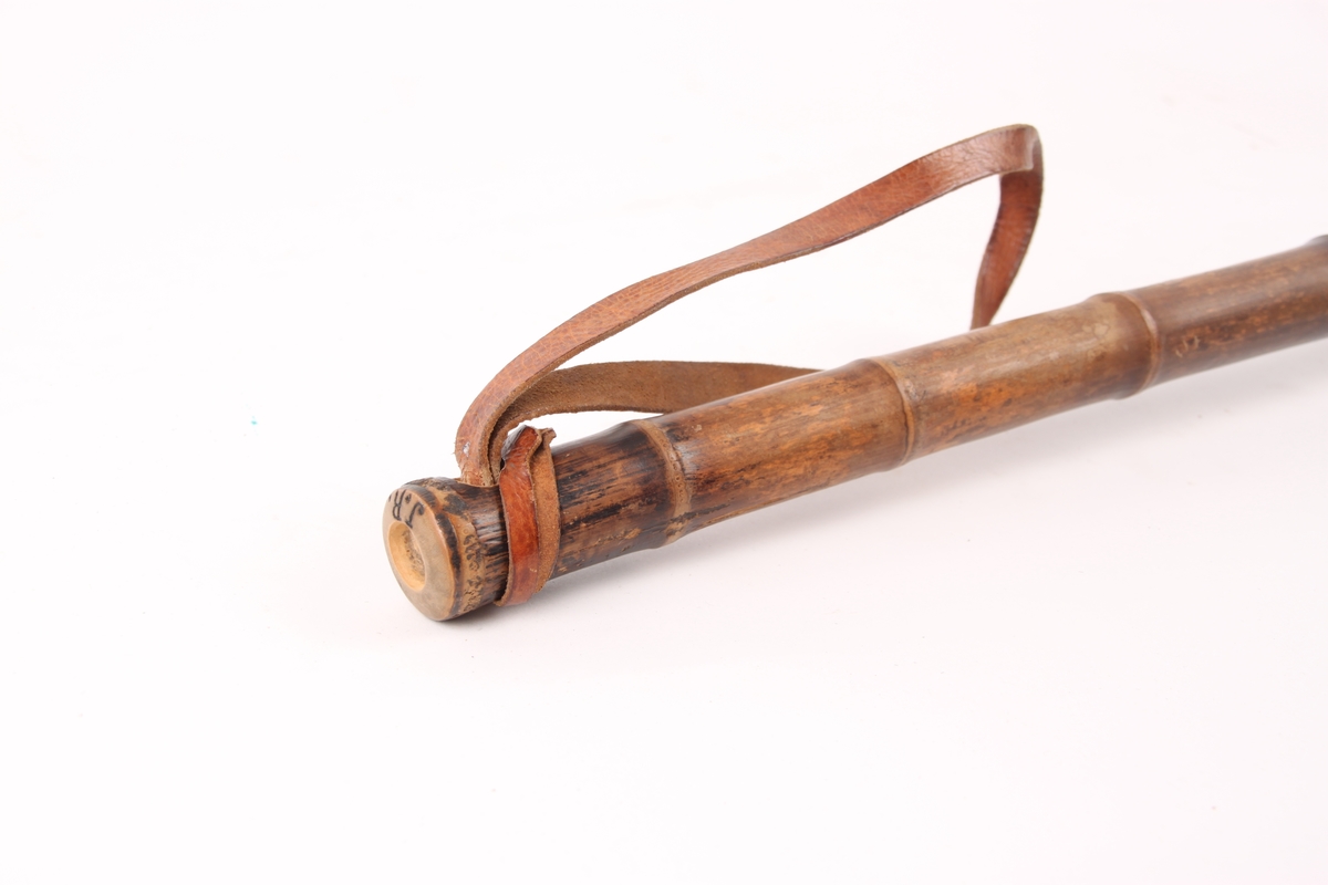 En bambusstav med trinse, stålpigg og lærrem.
