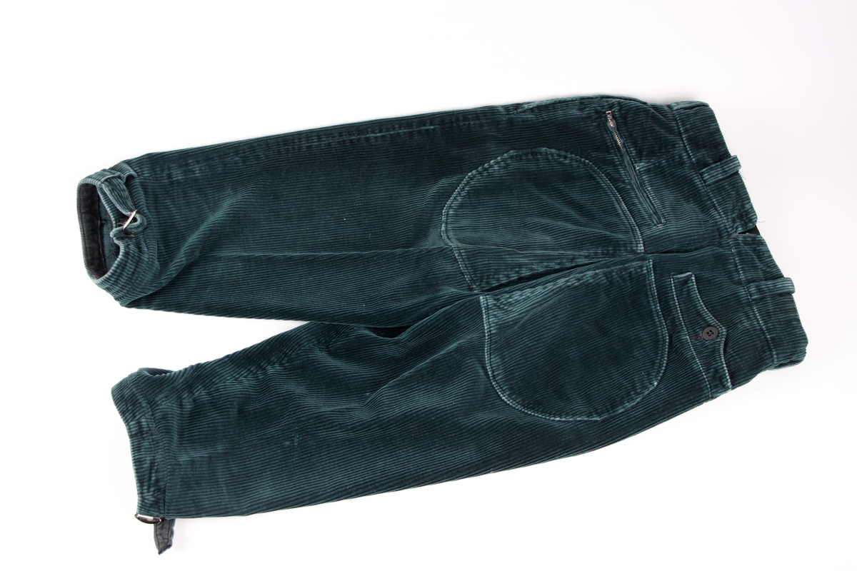 Flaskegrønn nikkers i kordfløyel med lommer og beltespenner nederst i buksebeina.