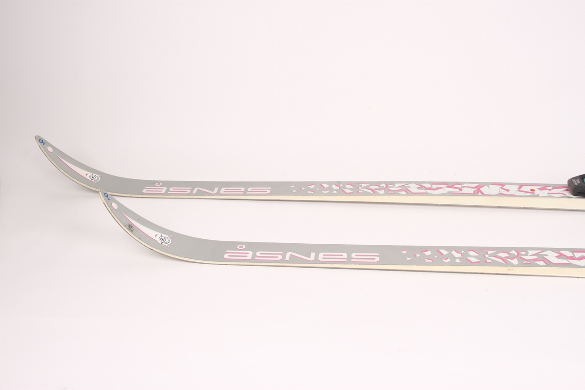 Et par ski med stålkanter og Salomon-binding. Til skiene er det festet en pose med to Salomon-bindinger.