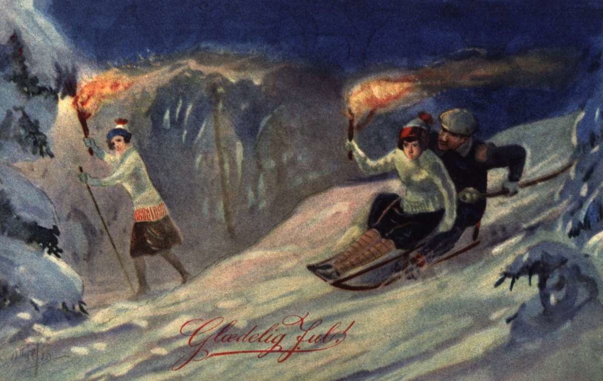 Julekort. Jule- og nyttårshilsen. Vintermotiv. Et par på kjelke og en skiløper med fakler i full fart gjennom skogen. Stemplet 1923.