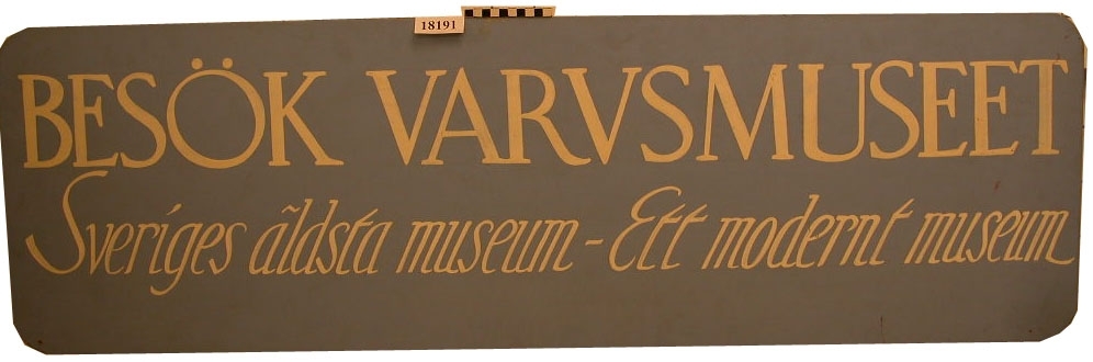 Rektagulär skylt av masonit med avrundade hörn. Liggande format. Målad på en ljusblå botten och med vit text fördelad på två rader " BESÖK VARVSMUSEUM Sveriges äldsta museum -Ett modernt museum ".
Baksidan har trälister till förstärkning.