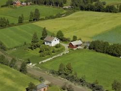 Engestad. Hvitt hus, lite rødt uthus. Hage med busker og træ