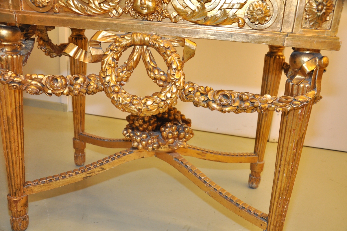 Bordet er av forgylt tre med toppplate av stein. Bordet er riklig utskåret. Bordet er i fransk ny-klassisisme, nærmere bestemt Louis XVI.