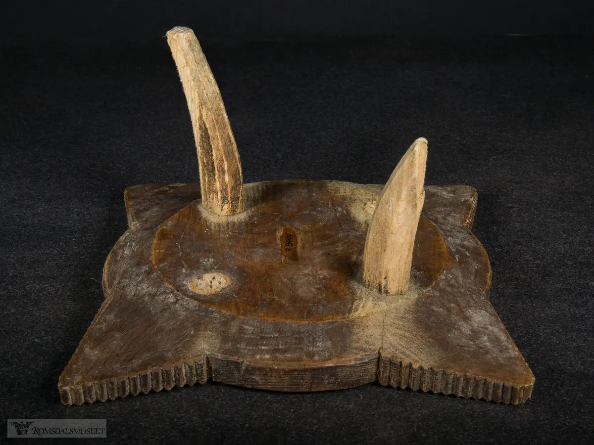 Utskjæring på fatet, små spisser i sirkler og på vinger. Ringene som omkranser midten minner om tannhjul.