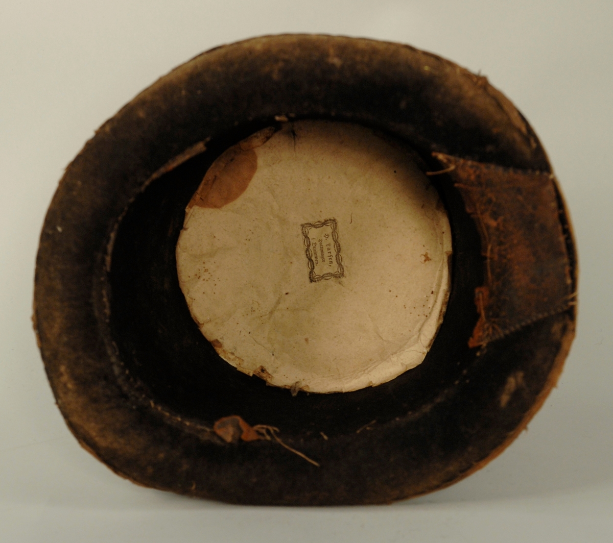 En skinnbit er satt på inne i hatten. Rundt kanten går et bomullsbåndsom skoning.