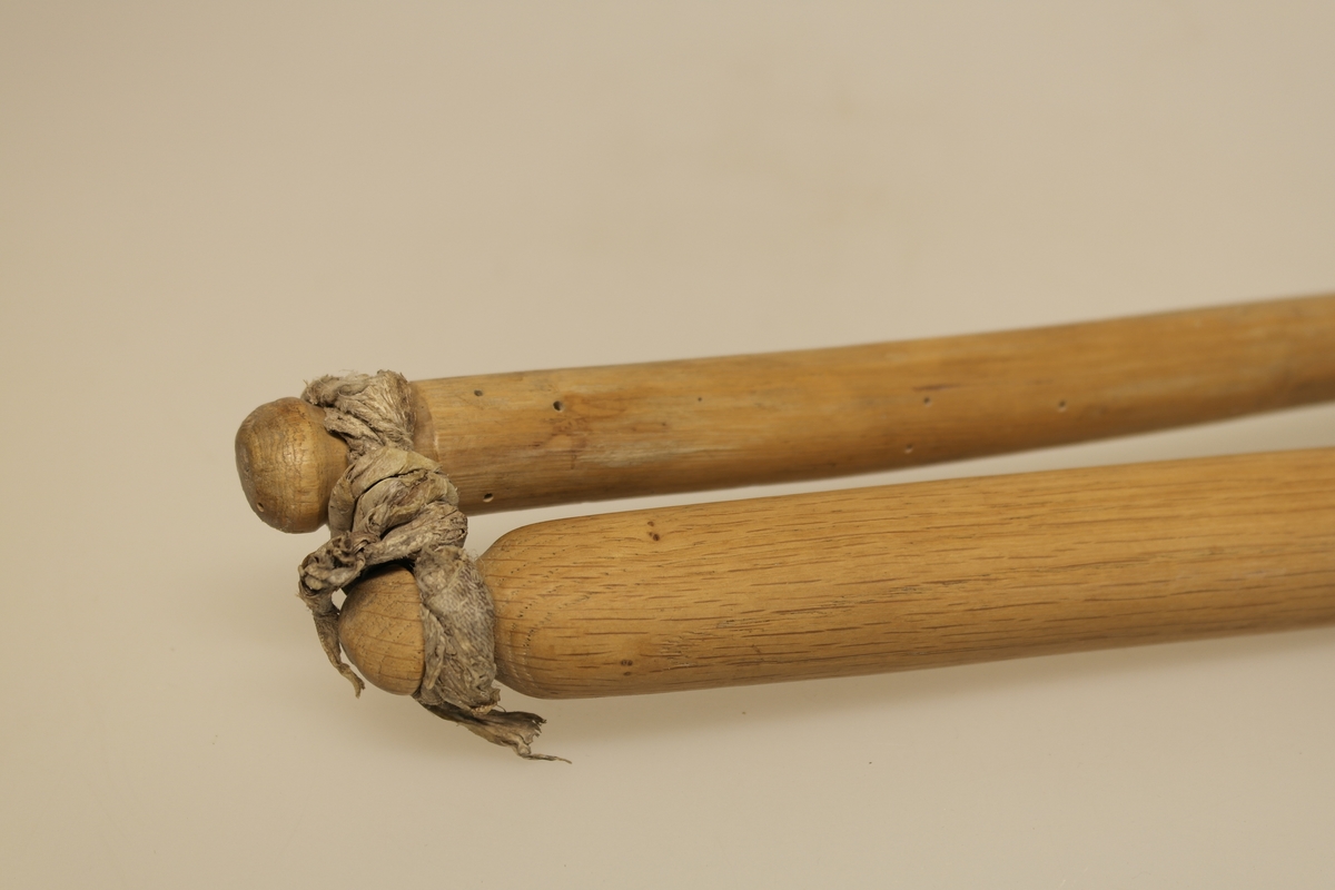 Sliul/Treskestav i skåret eik, bestående av to stokker, en stang/håndstav og en slagstav. De to stokkene er bundet sammen med åleskinn. Ble brukt til å treske korn med.