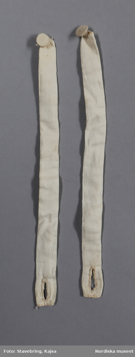 Katalogkort finns.

Bruddräkt bestående av a. kjol, b:1-2. tröja. c. band.

Kjol och tröja av vit tunntrådig tätvävd bomullslärft


b:1. Tröja, kort med skört i sen 1700-talsmodell. 
2 framstycken/sidstycken  och 2 ryggstycken kraftigt avsmalnande ned mot skörtet bestående av 4 veck som hålls samman med några stygn Som dekor vid skörtet två sammanhängansde tofsar av vitt bomullsgarn, gjorda som en "smällkaramell" som lindats på mitten med utstående trådar åt sidorna som bildar tofsarna. Infällda skörtkilar i sidorna. Smal fåll i nederkanten med en rad efterstygn. Isydd ärm med skarvkilar under armen, på axeln 9 lagda veck, rak ärmkant. Vid halsringning, knäppning saknas. Helfodrad med vit linnelärft ned till midjan, skörtet ofodrat. I midjan ripsband i linne smalrandigt i blått och rosa på vit botten, 8mm brett, fastnäst med några stygn på 3 ställen. Knyts fram. Runt detta band är påknäppt 2 sydda band (b:2+) av bomullstyget, 1,5 cm breda försedda med en tygknapp och knapphål i ändarna.. Kan troligen ha knäppts fast runt ärmarna vid handleden.
/Berit Eldvik 2008-12-11