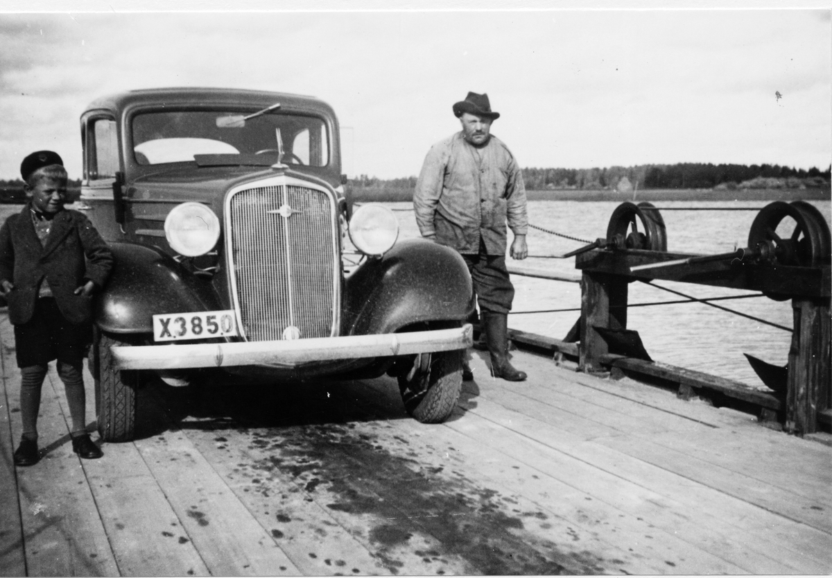 Färjan vid Norra Sundet 1935.
Färjkarlen Anders Andersson (Färkar-Anders).
Bilen (en Chevrolet 1934-1935) är Valfrid Lindbloms taxibil.
Till vänster: Erik Lindblom (son till Valfrid).