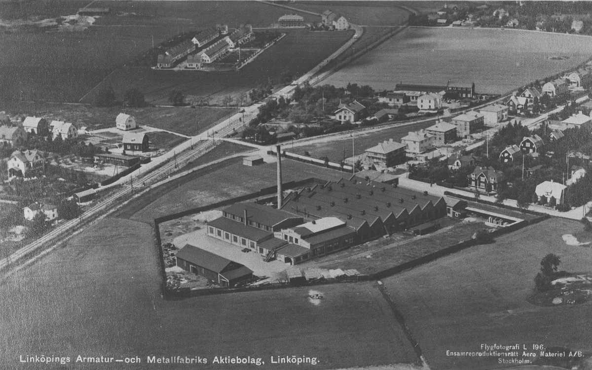 Bildtext: Linköpings Armatur-och Metallfabriks Aktiebolag, Linköping.
Flygfoto i nordvästlig riktning. Till vänster ser man en gata och ett järnvägsspår, på dess vänstra sida ser man delar av Tannefors. Till höger ser man Råberga.