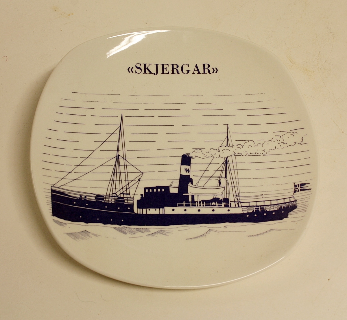 Avrundet, rektangulært fat med bilde av båten "Skjergar".  Gave fra Øygarden kommune til Kystmuseet i Øygarden.