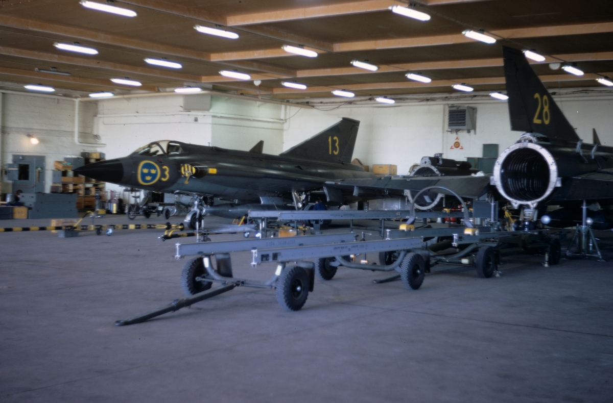 Flygplan J 35 nummer 13 och 28 står i en hangar på F 3 Malmen, våren 1973. Underhåll pågår.