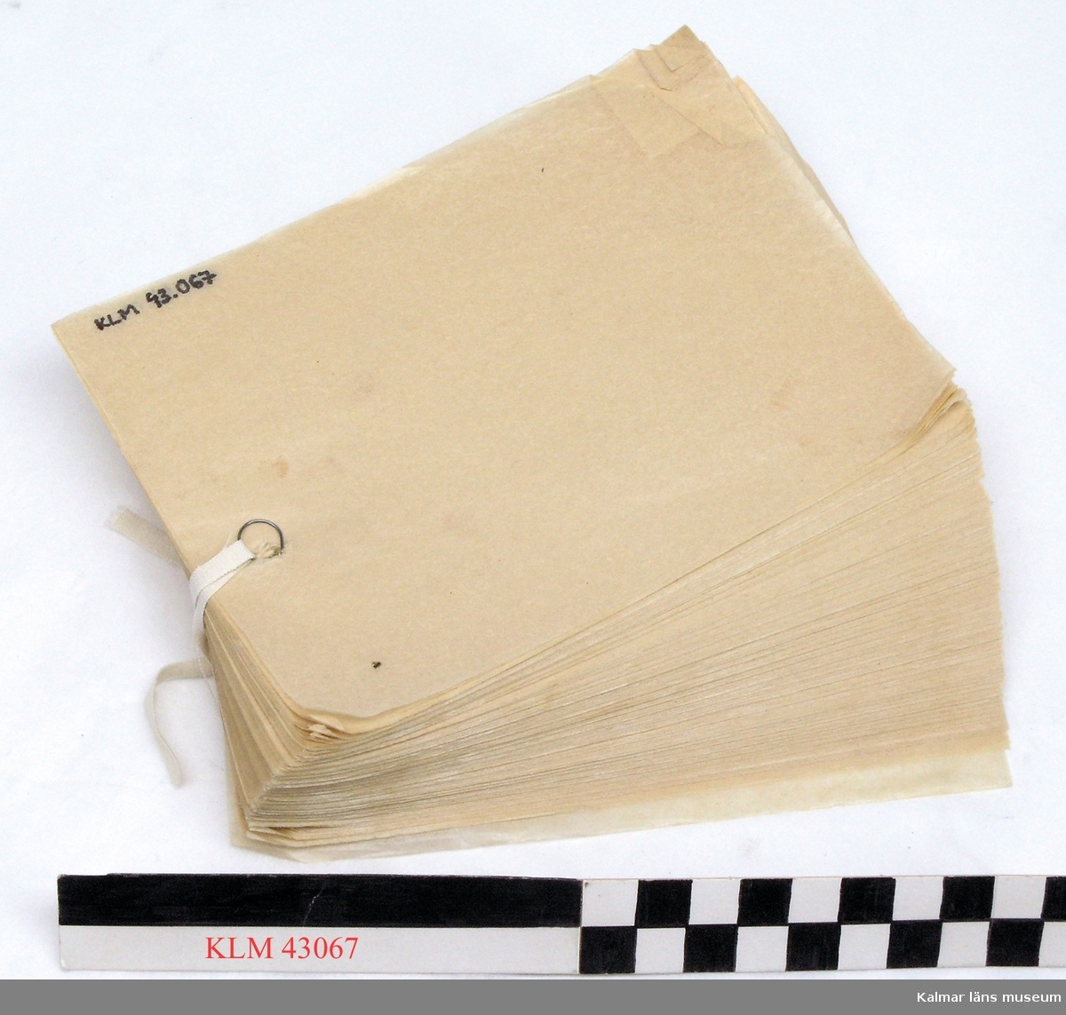 KLM 43067 Toalettpapper, en bunt. Rektangulärt ark av tunt papper, hål mitt på ena kortsidan.