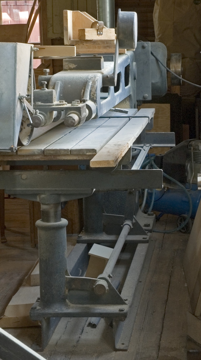 Bandputsmaskin med höj- och sänkbart putsbord av trä. Maskinen drivs direkt av elmotor. Putsbordet kan, på hjultrissor av järn, rullas in eller ut under putsbordet. Putsbandet av sandpapper löper horisontellt över två skivor. Till bandputsen hör två putsklotsar.

Funktion: Maskin för putsning av trä