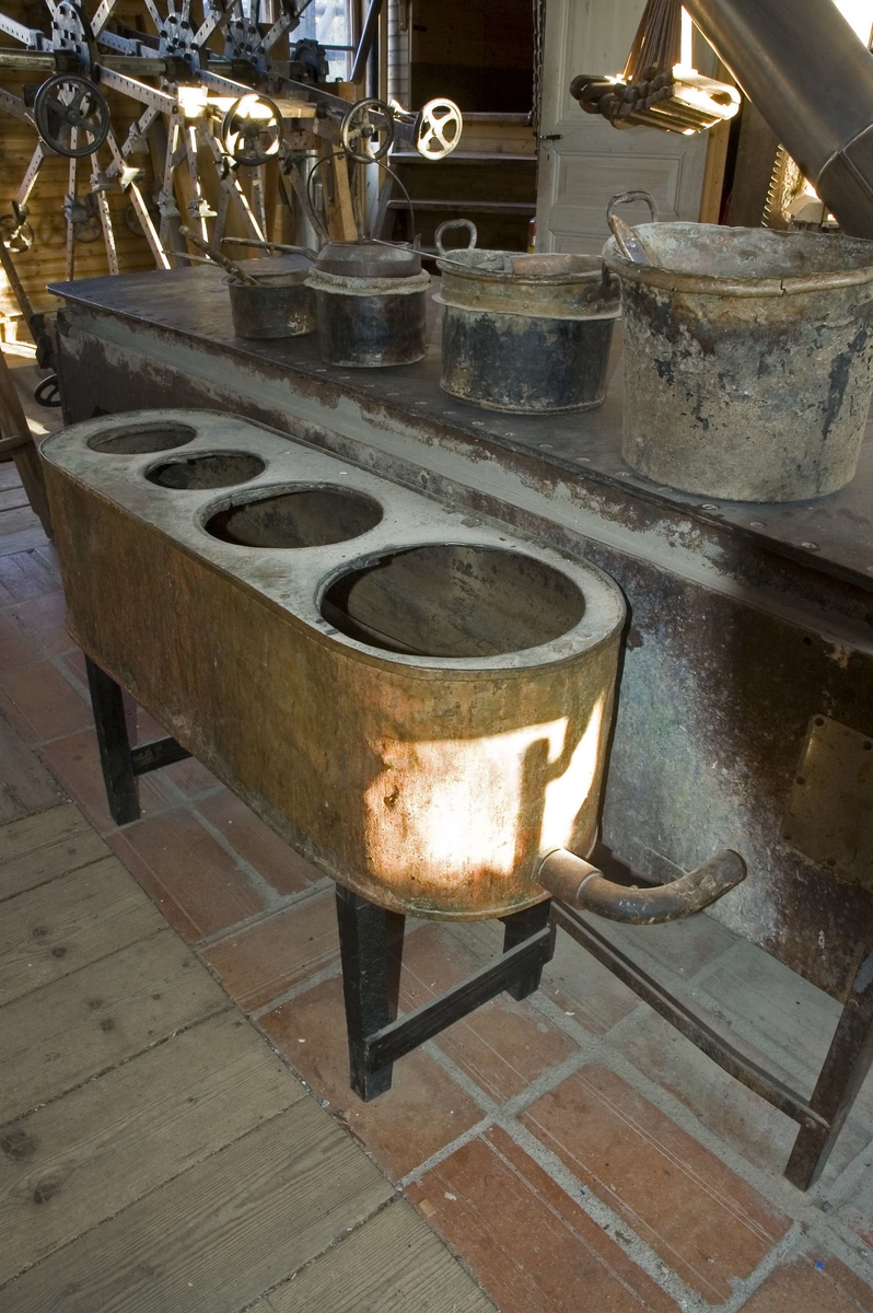 Limhäll med stativ av järn med sex ben. Limhällen har formen av ett bord med järnplatta. På den ena kortsidan, utanför järnhällen finns en låda av plåt med lucka på ovansidan som är öppning till eldstaden för uppvärmning av hällen.
Eldningsplatsen fortsätter ett stycke in under järnplattan och värmer upp det vatten som cirkulerar i kanaler av stål i en låda under plattan. Järnplattan värms upp av det varma vattnet och på den varma hällen värms virke och limplattor upp före limning med benlim som är ett så kallat glutinvarmlim.
Limhällen är rostig. Den används ej på Snickerifabriken.

Funktion: Värmning av virke och limplattor