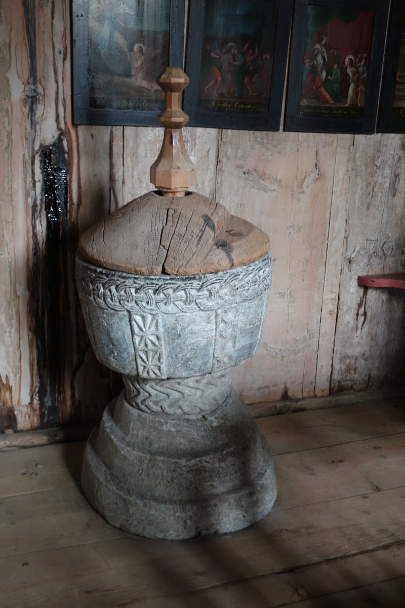 Døpefont av kleberstein i kalkform. Fonten er hogd i to deler. Foten er trappeformet med tre trinn. Cupa er dekorert med en type ringkjede på stetten og en annen type ringkjede øverst. Midtdelen er dekorert med nedsenkede stjerner i vertikale bånd, som i karveskurd. Stort hulrom i cupa. I bunnen og gjennom fotstykket er det et uttappingshull, med en treplugg som kork. Til fonten hører det et lokk av tre, med påsatt spir som håndtak. Lokket er gammelt, spiret er nyere. På lokket er det et hakk, med restene av to treplugger. Dette er restene etter en låseanordning for å kunne låse lokket fast til fonten.